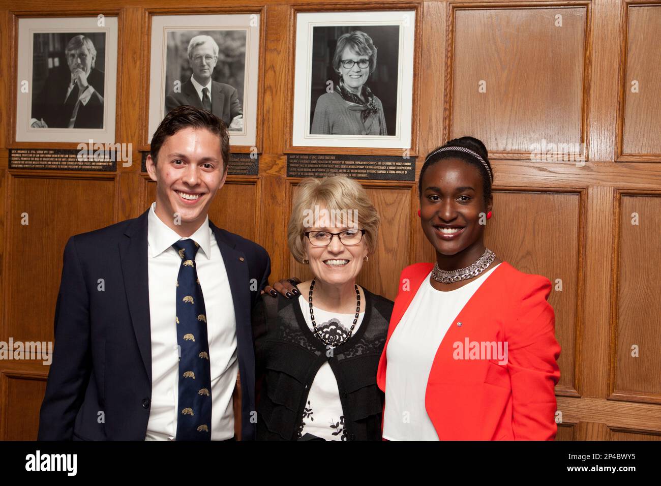 Adam Kleven, left, and Kendall Johnson, right, pose for a picture with University of Michigan President Mary Sue Coleman after the unveiling of a bronze plaque honoring Coleman at the Michigan Union in Ann Arbor, Mich., on July 1, 2014. The plaque honoring Coleman, U-M's 13th president, adds her portrait and service tribute to the display of U-M presidents. (AP Photo / The Ann Arbor News, Patrick Record) Stock Photo