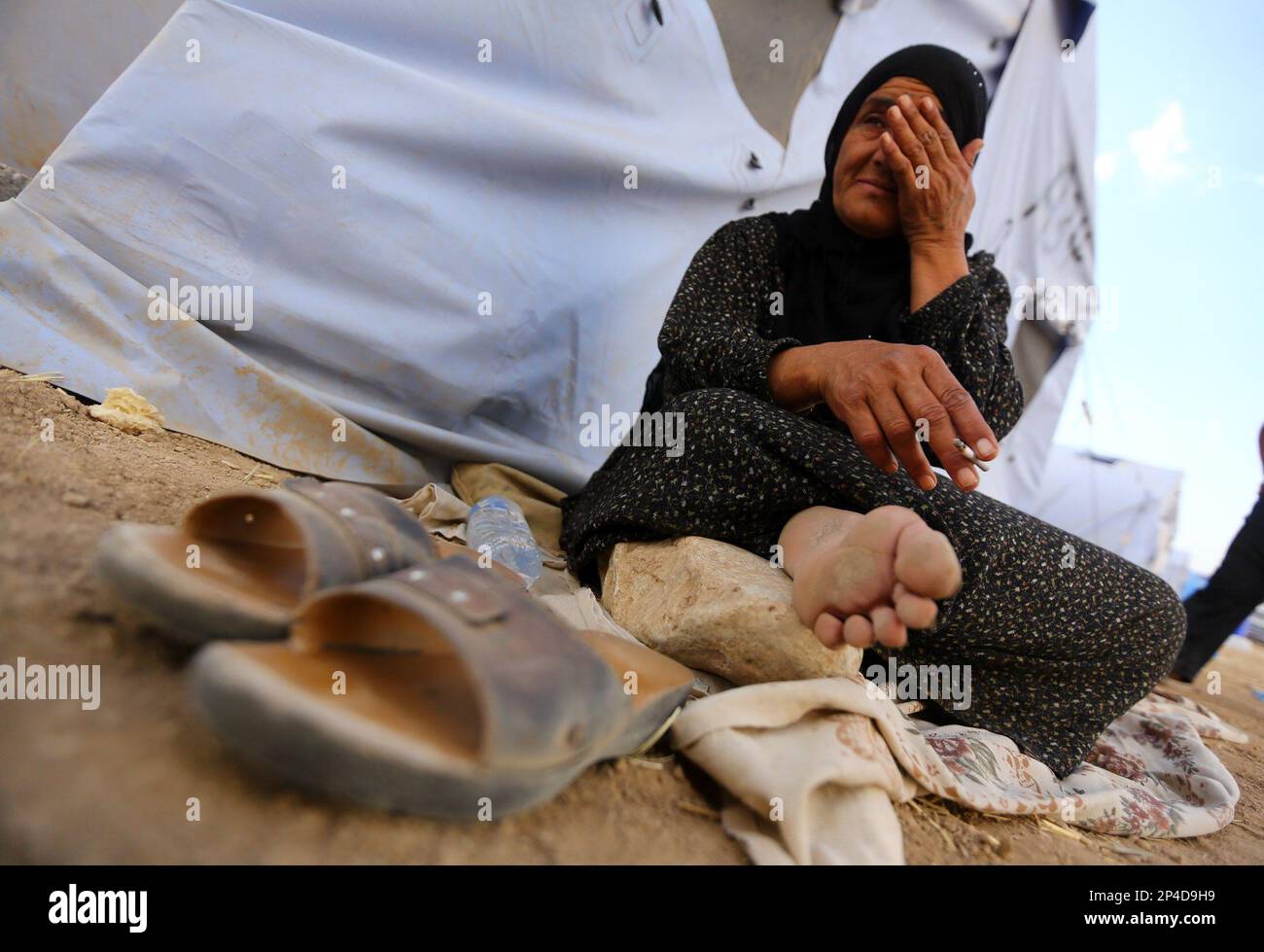 An Iraqi refugee woman from Mosul sits outside her family's tent at Khazir refugee camp outside Irbil, 217 miles (350 kilometers) north of Baghdad, Iraq, Friday, June 13, 2014. The Islamic State of Iraq and the Levant, the al-Qaida breakaway group, on Monday and Tuesday took over much of Mosul in Iraq and then swept into the city of Tikrit further south. An estimated half a million residents fled Mosul, the economically important city. (AP Photo) Stock Photo