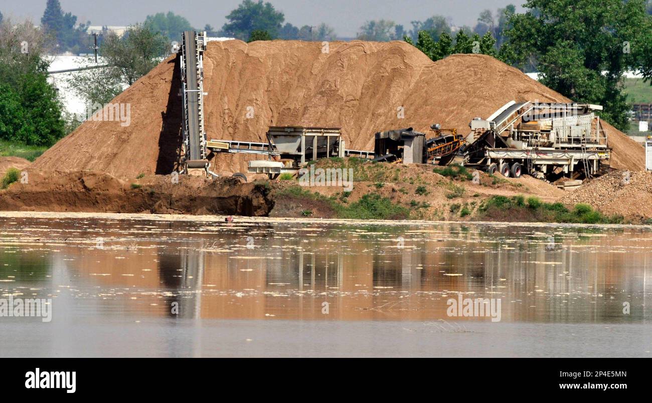 Water surrounds mounds of dirt and equipment as the Poudre River spills into the Varra Gravel