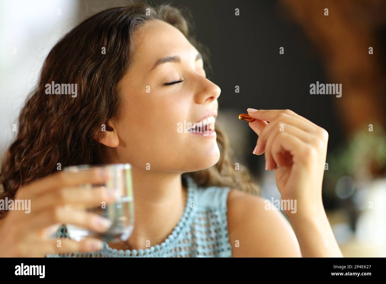 Happy woman eating a vitamin pill in a restaurant Stock Photo