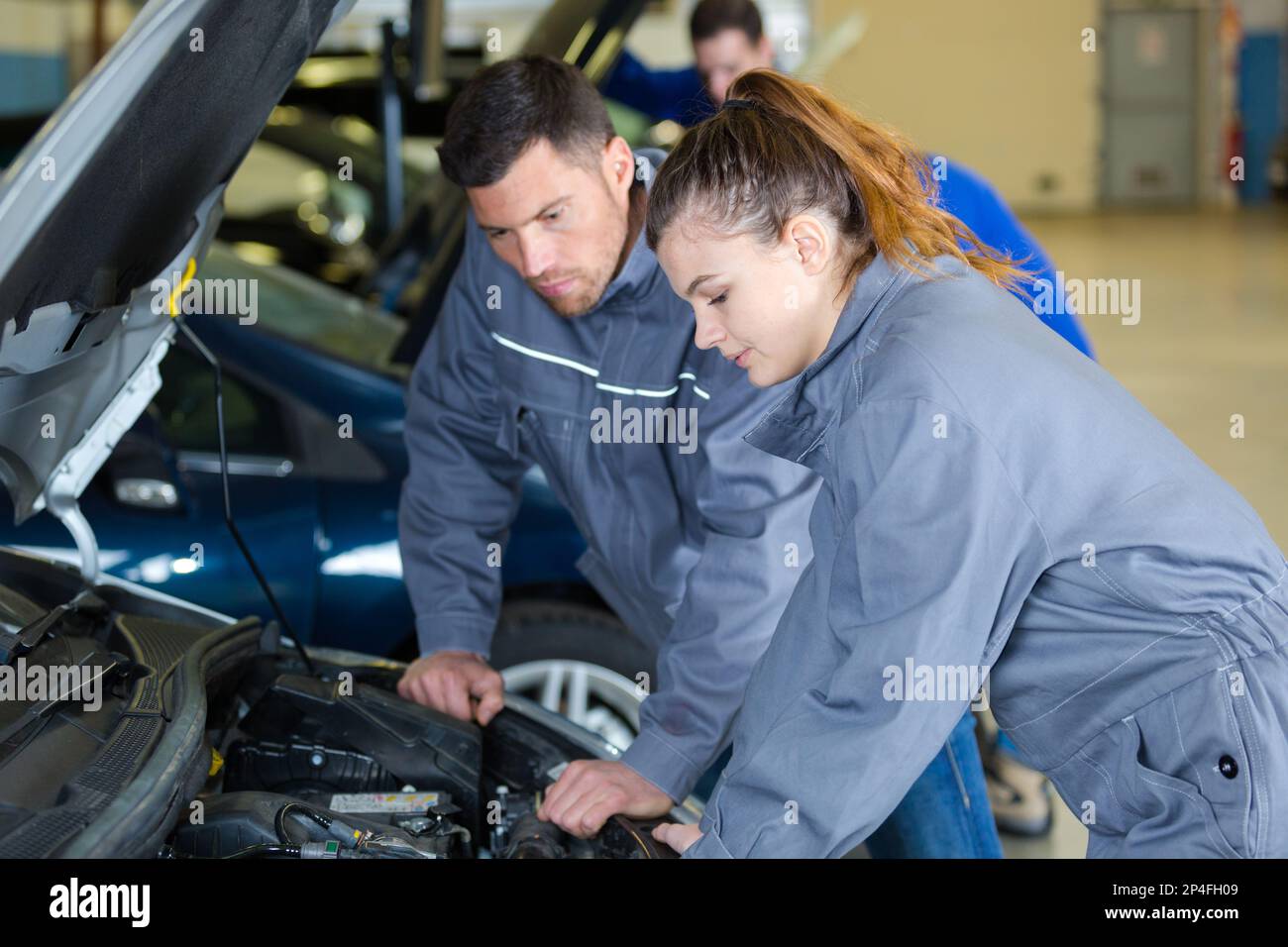 mechanic and apprentice looking at cars engine Stock Photo - Alamy