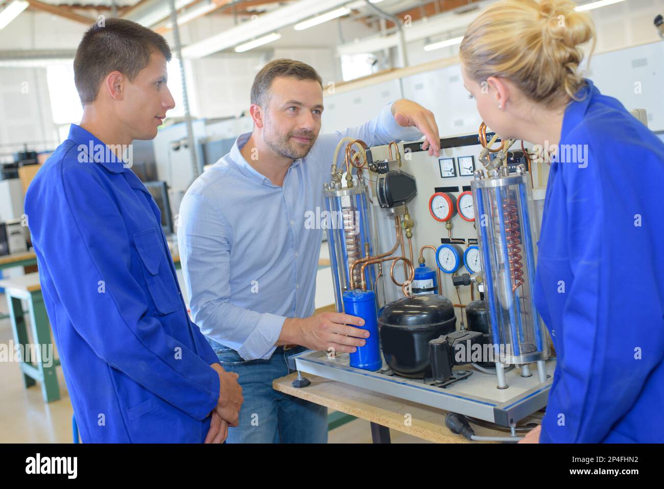 engineer in factory with apprentices checking components Stock Photo