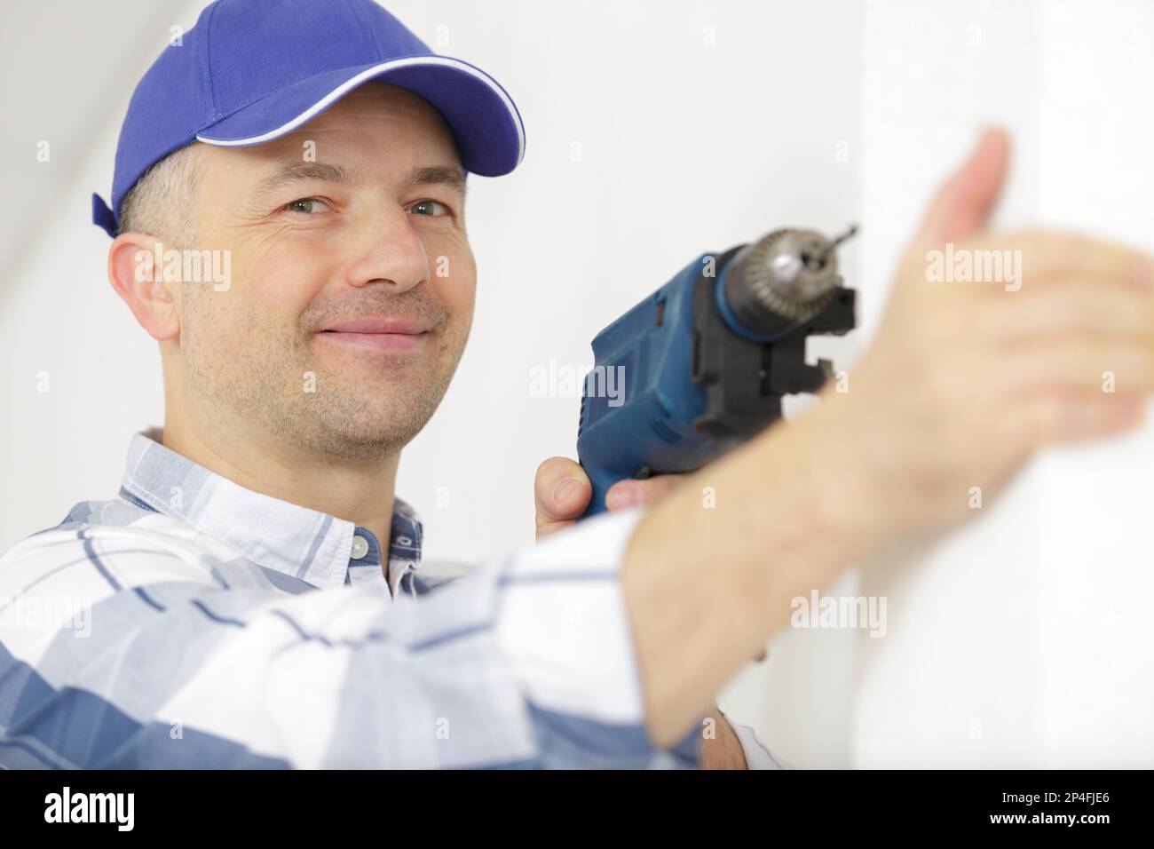 construction worker using electric drill on building site Stock Photo
