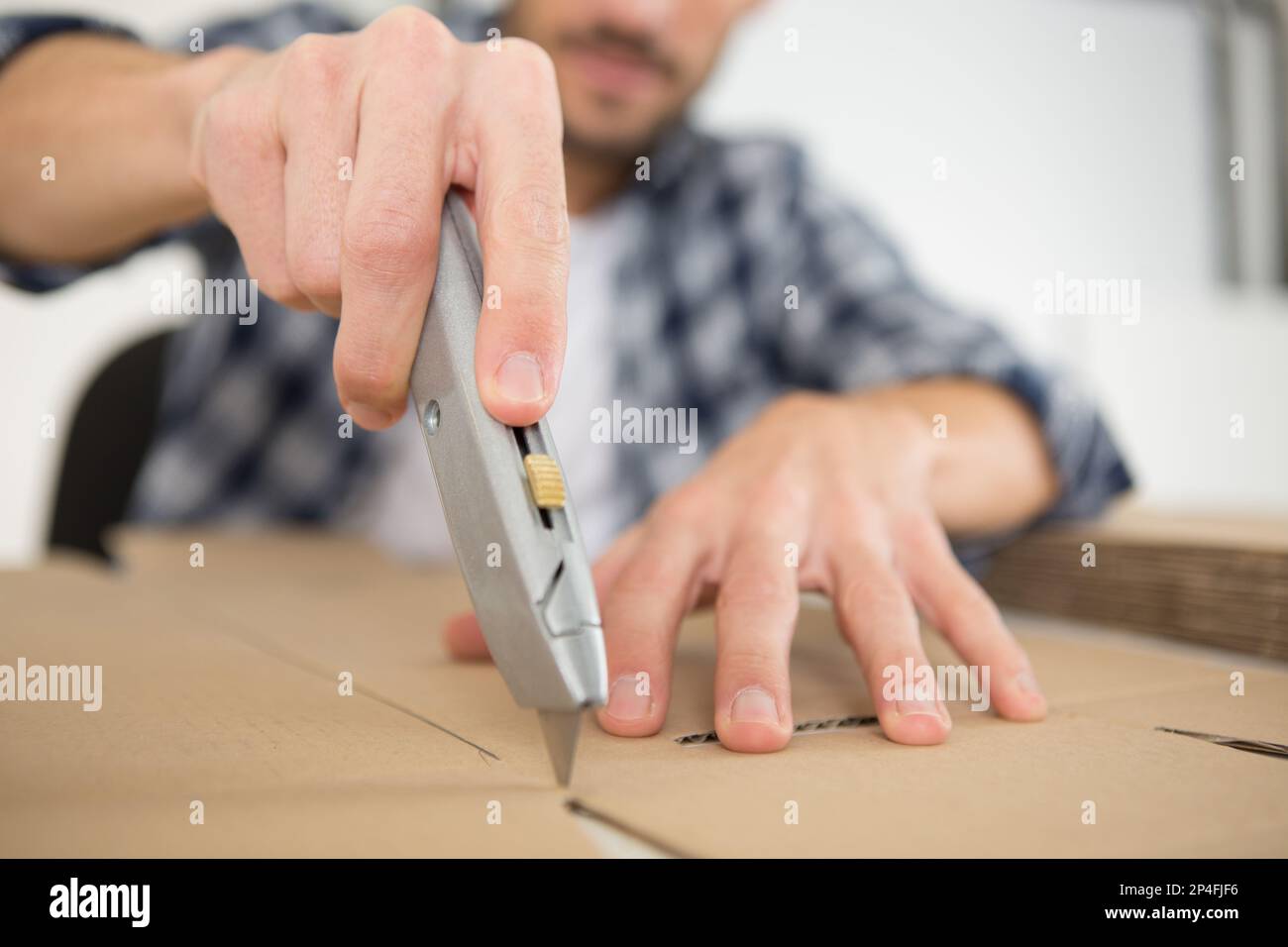 man using an utility knife to open a cardboard box Stock Photo Alamy