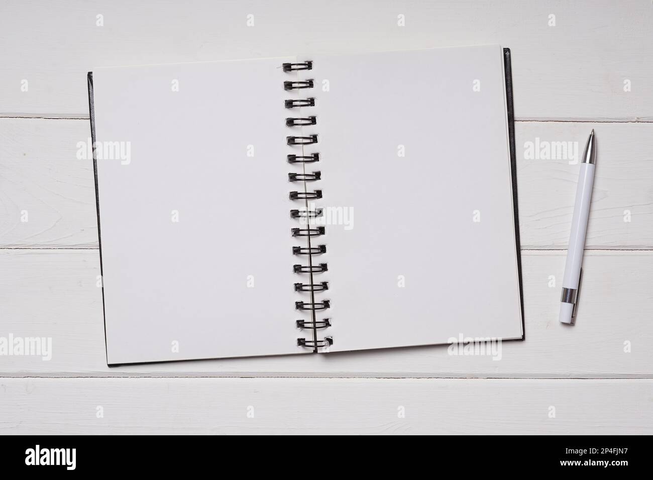 spiral binding notebook with blank pages and pen on white wooden desk Stock Photo