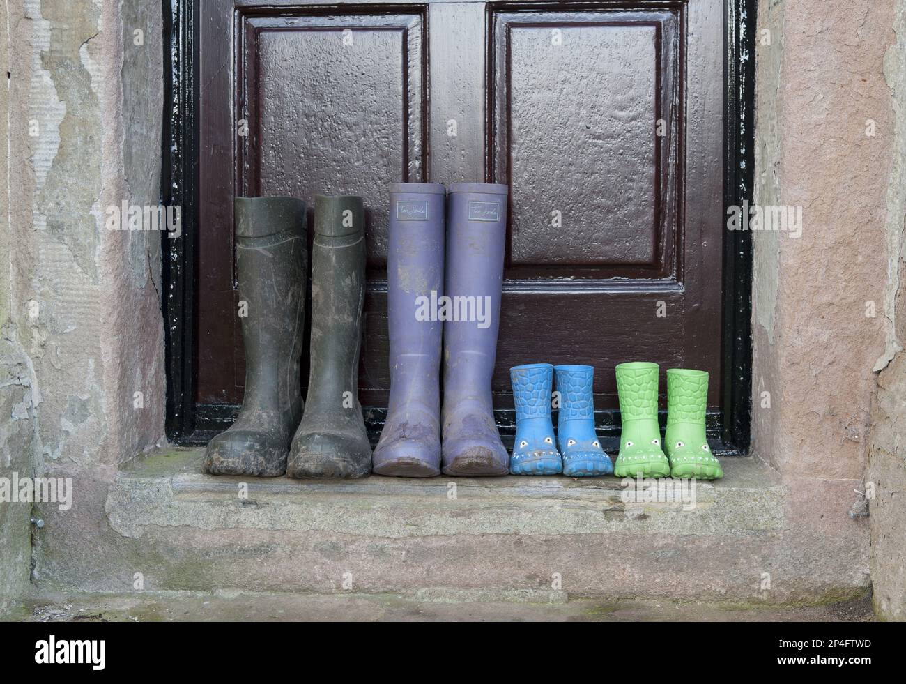 Four pairs of wellies, two pairs of children's boots, one pair of ladies' boots and one pair of men's boots, outside the farmhouse door, Whitewell Stock Photo