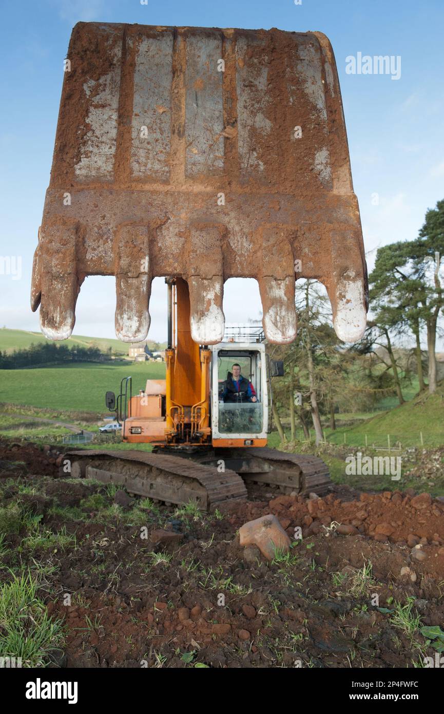 Excavator digging stone on slope, England, United Kingdom Stock Photo