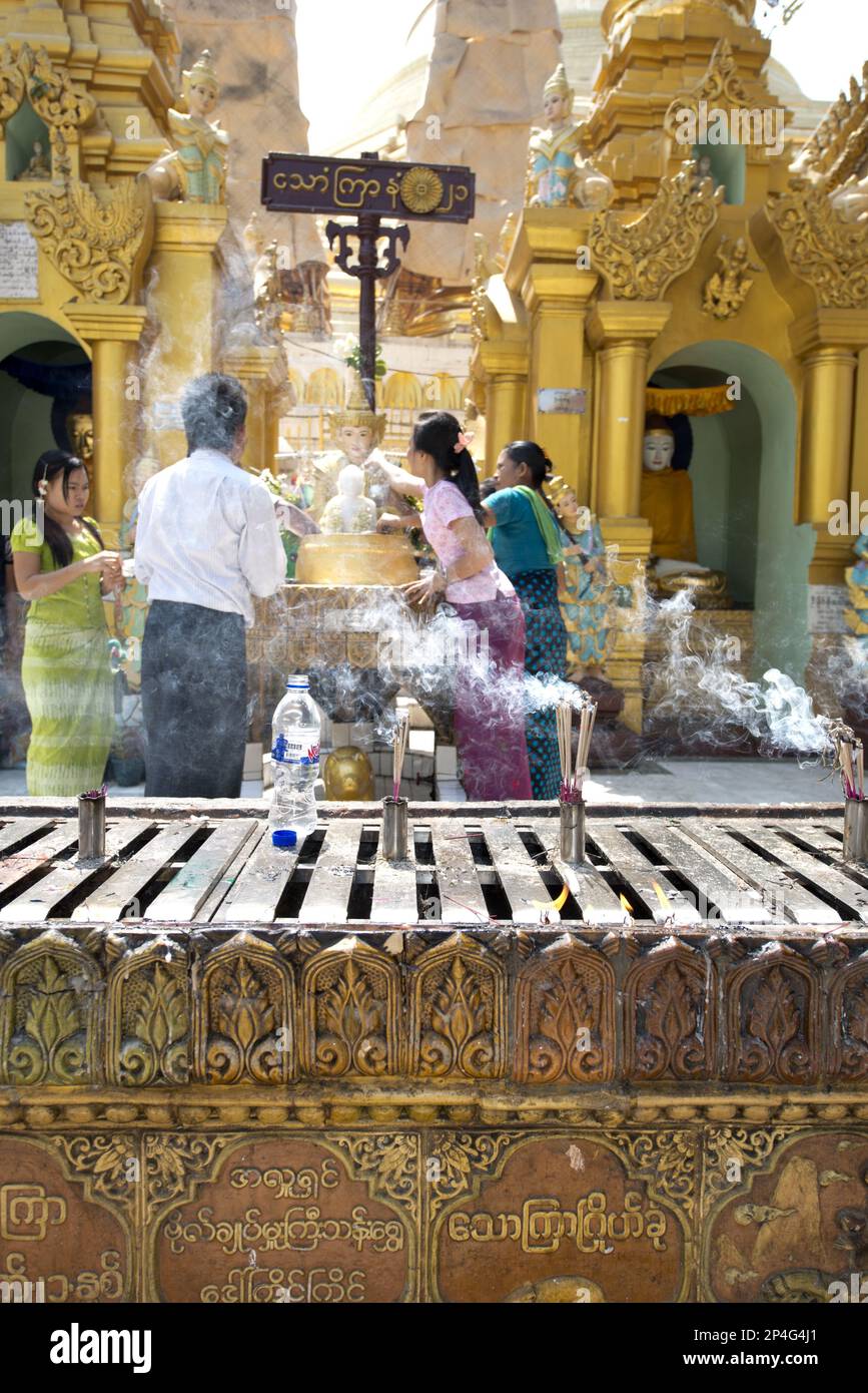 Smoke from burning incense with people at the Buddhist altar, Shwedagon Pagoda, Yangon, Myanmar Stock Photo