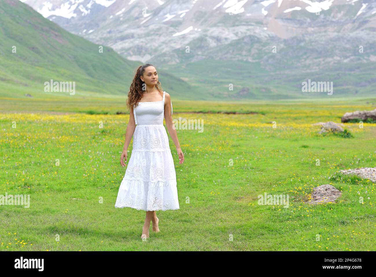 Front view of a woman in white dress walking in the mountain Stock Photo