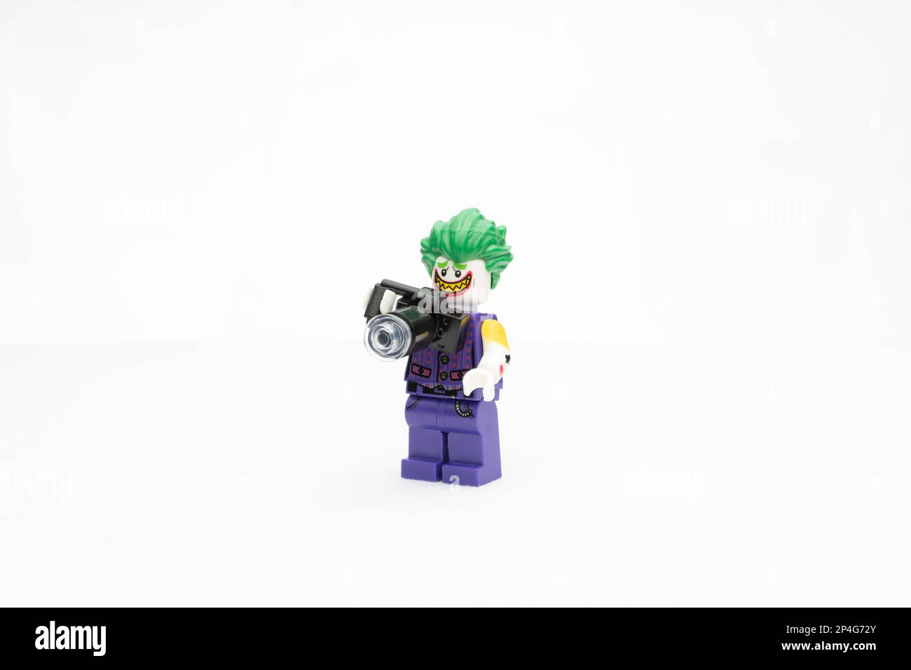 A Lego Joker figurine holding a camera in its hand, isolated on white