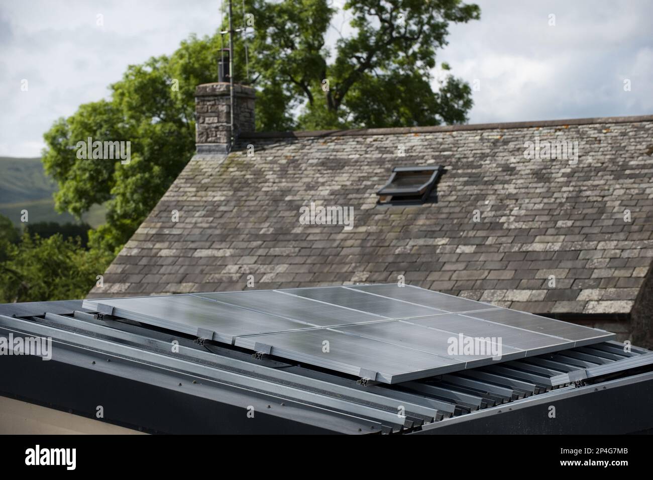 Solar energy panels attached to the garage to provide electricity for a house in a rural setting, England, United Kingdom Stock Photo