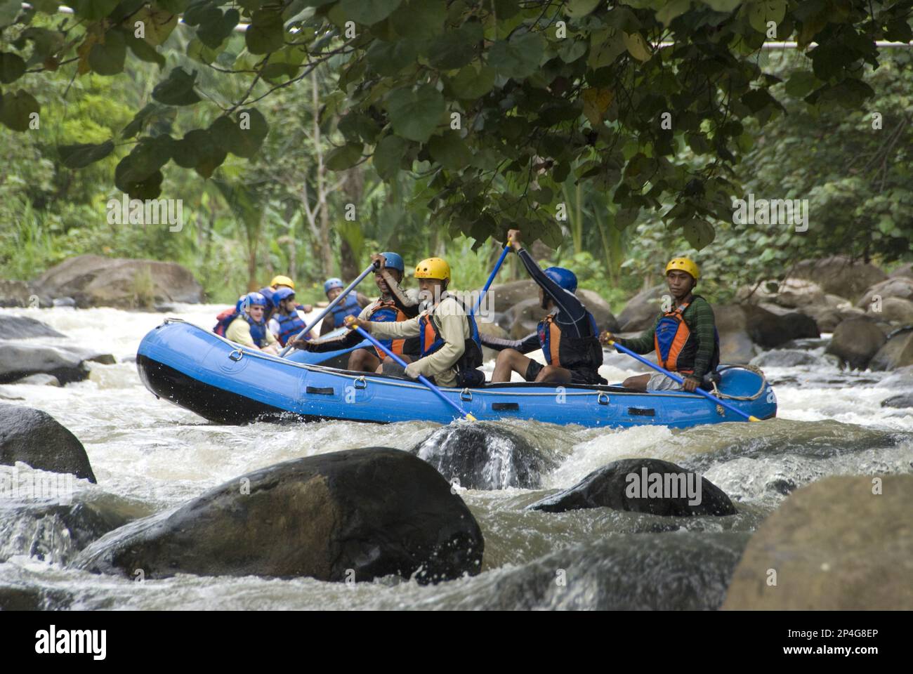 People wearing hard hats and life jackets, rafting in rapids in Dingys