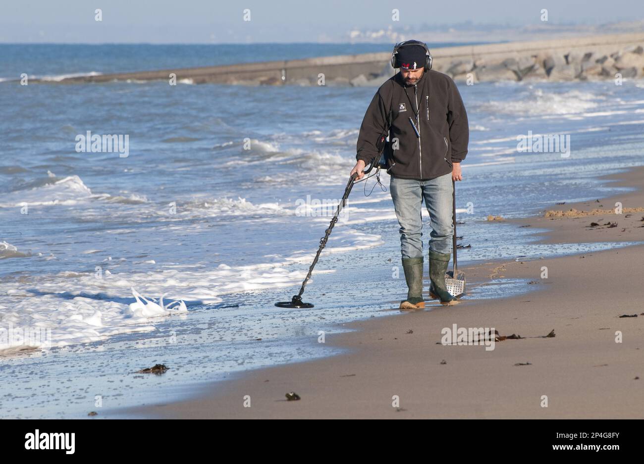 Man using metal detector on beach, near Granville, Manche, Normandy, France Stock Photo