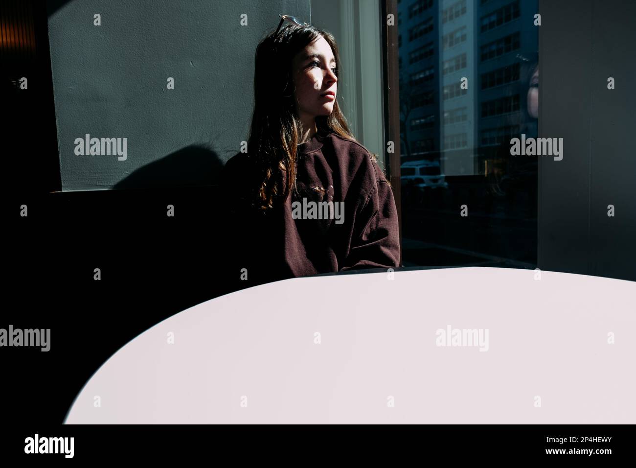 Teen girl looking out window on sunny day Stock Photo