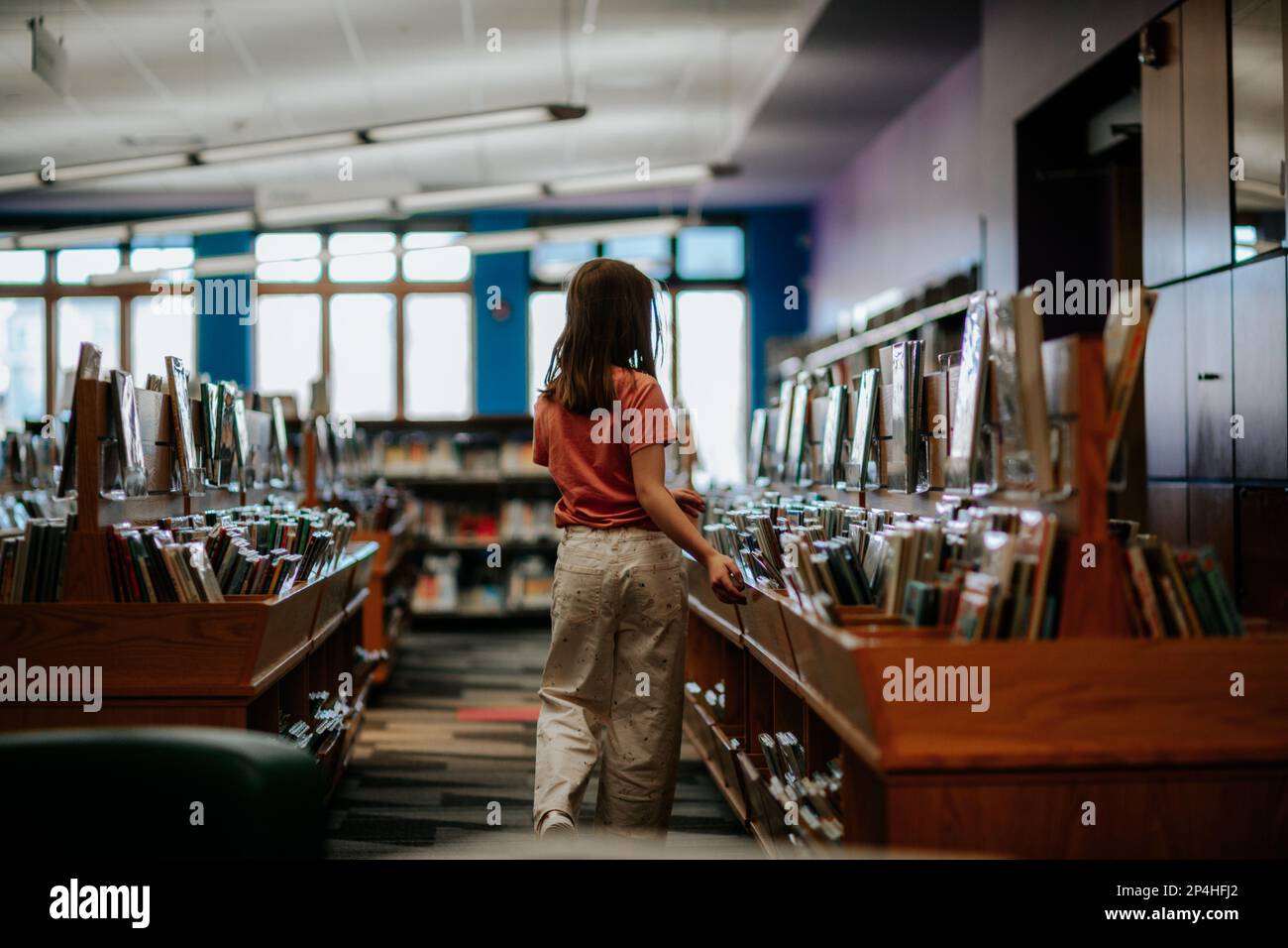 Back side of young girl looking at books inside Stock Photo