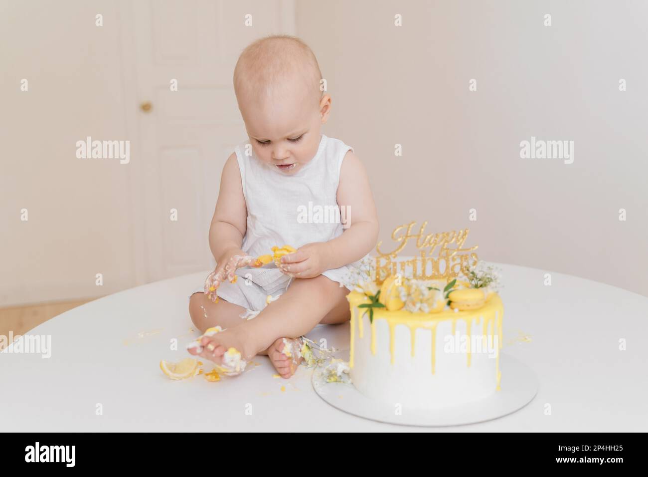 Baby girl eats her first birthday cake with her hands and legs Stock Photo