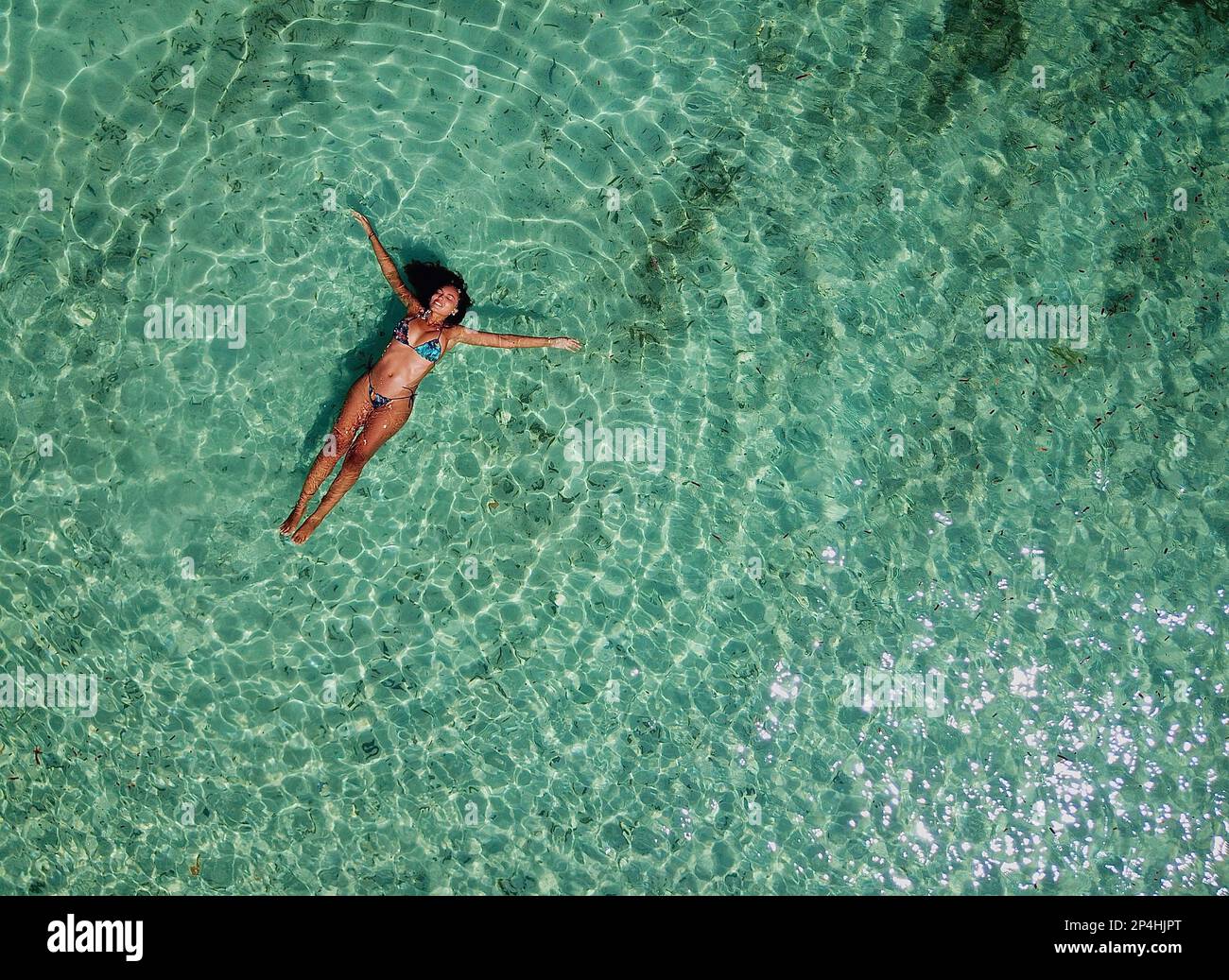 Aerial view of Young adult Female floating on crystal turquoise water. Stock Photo
