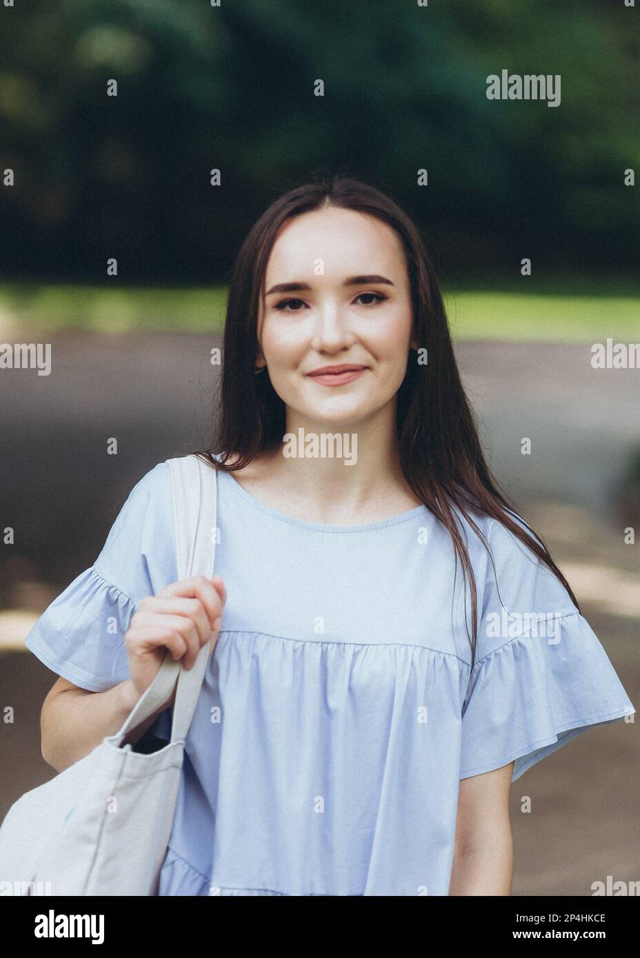 young brunette woman in a blue dress in the middle of the park Stock ...