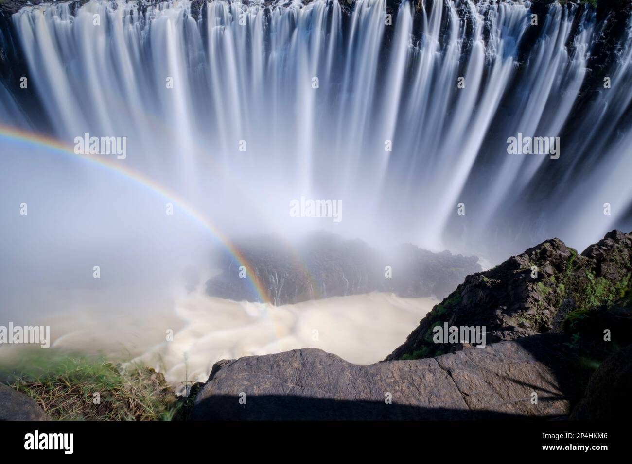 Waterfalls with rainbow, water falling down deep into the gorge. Victoria Waterfalls, Zambia, Africa Stock Photo