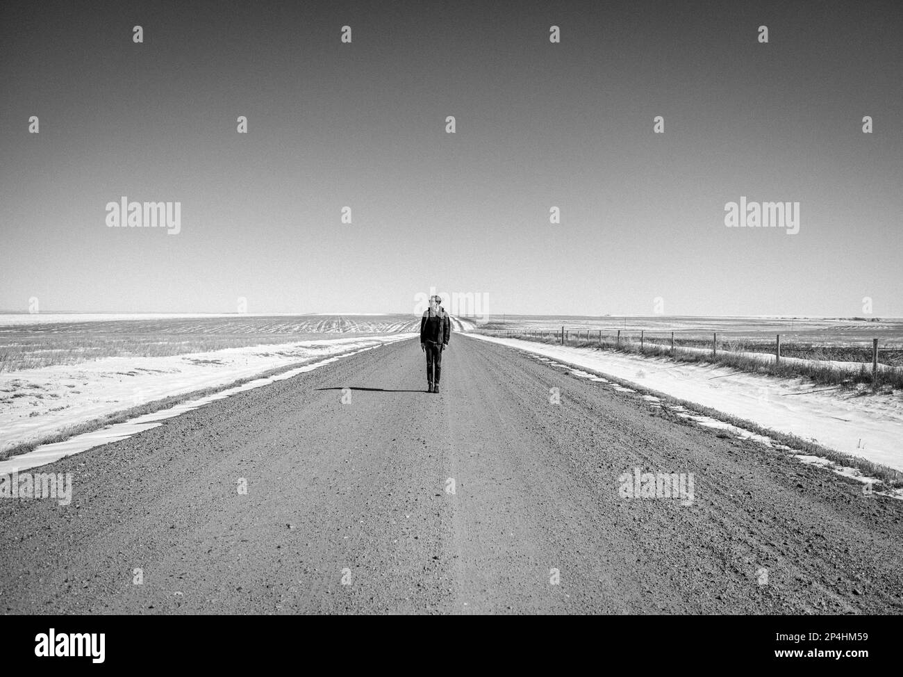 Man stands in solitude along lonely gravel road in Kansas Stock Photo