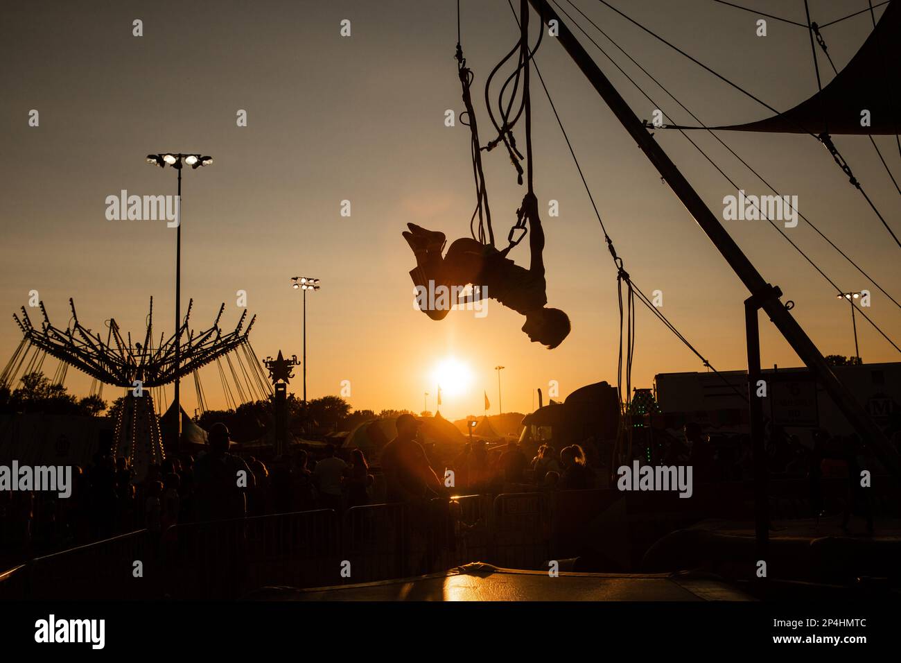 Kid flipping on trampoline at fair in evening Stock Photo Alamy