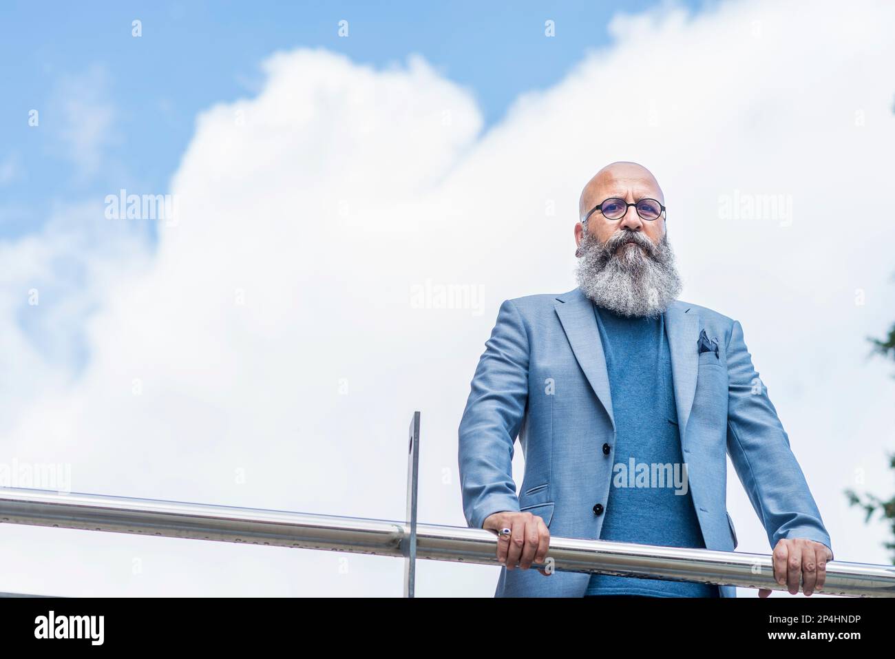 hipster man leaning on a fence looking at the camera Stock Photo