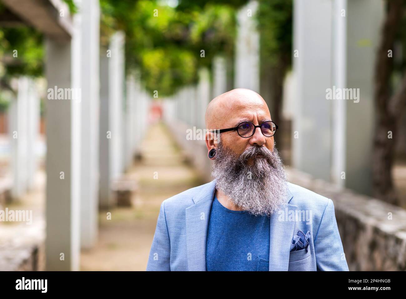 man posing standing with his hands in his pockets in a city park. Stock Photo
