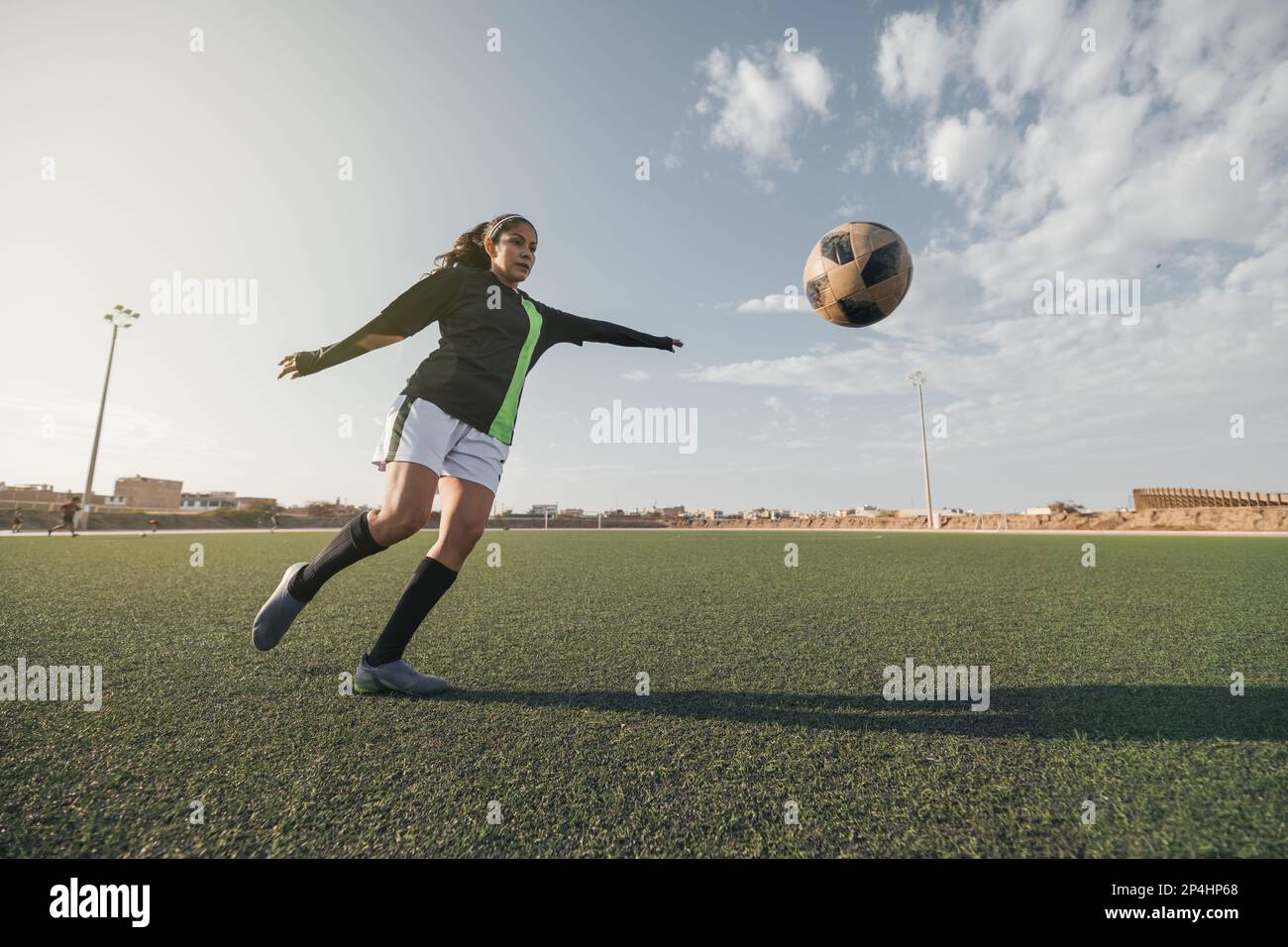 Young female soccer player kicking ball in a stadium Stock Photo Alamy