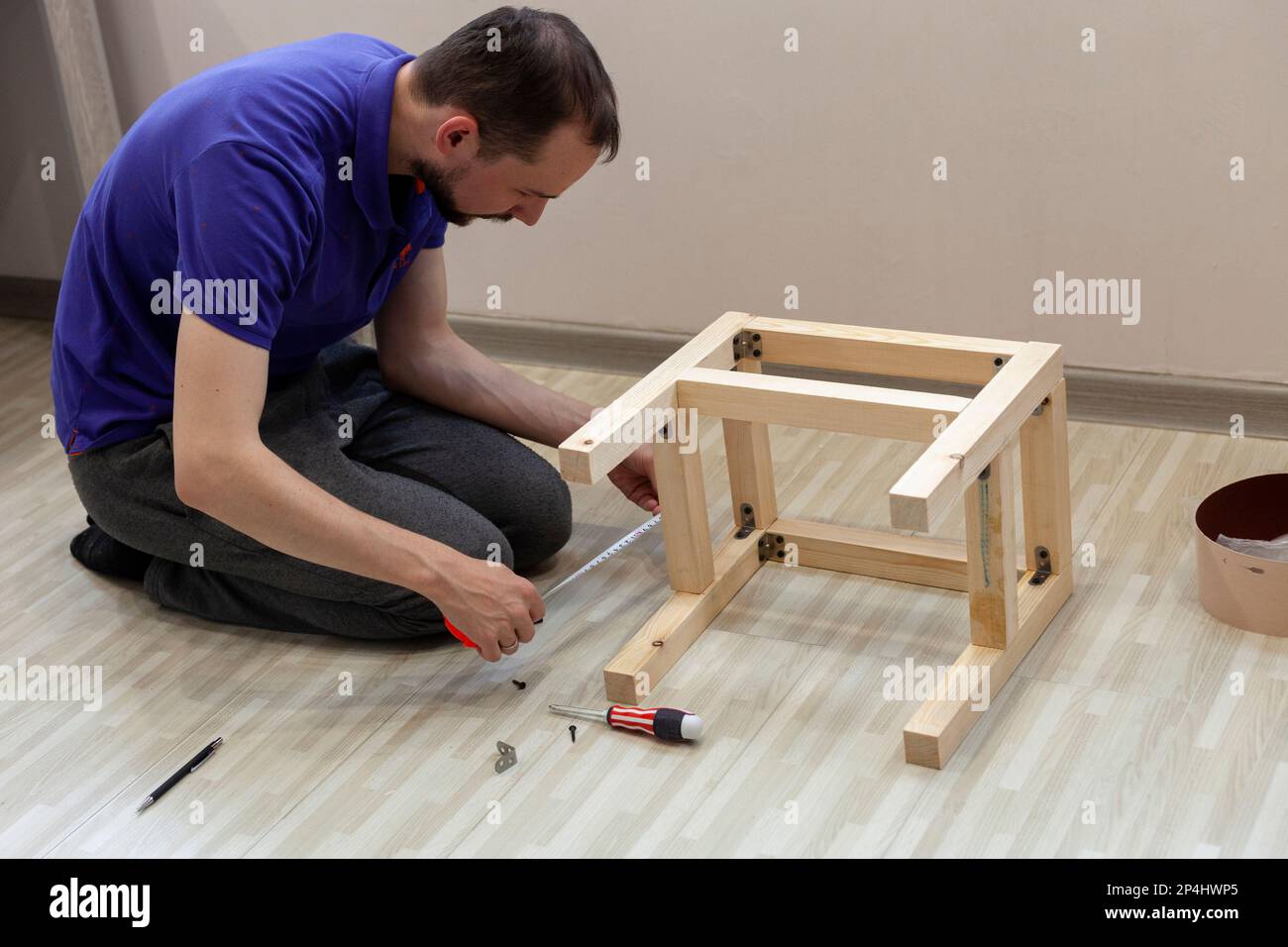Man with a tape measure measures the detail of the wooden stool Stock