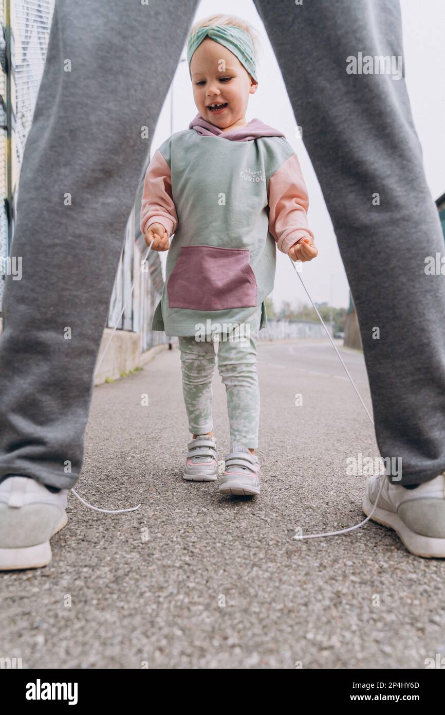 stylish baby girl in a hoodie hooligan unties dad's shoelaces Stock Photo