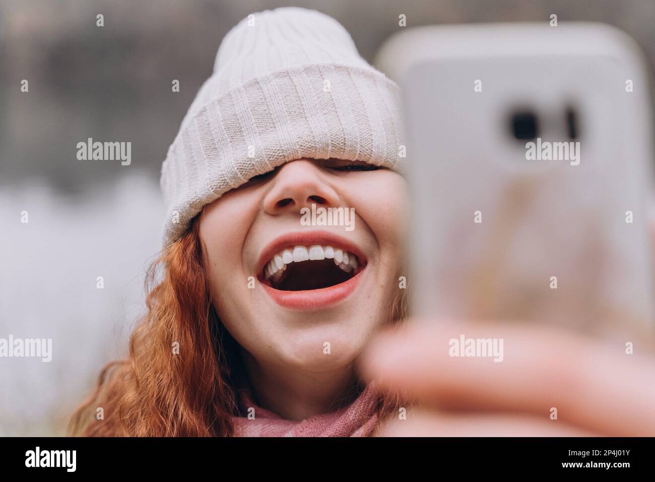 Curly redhead woman 30-35 with a hat over her eyes, she laughs Stock Photo