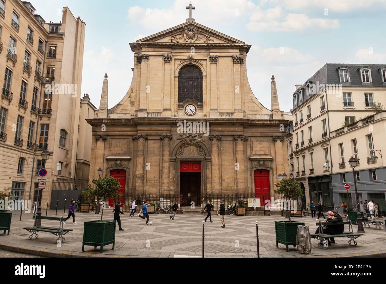 Boys playing football in front of the Basilica of Notre-Dame des Victories, in the 2nd Arrondissement Paris. Stock Photo