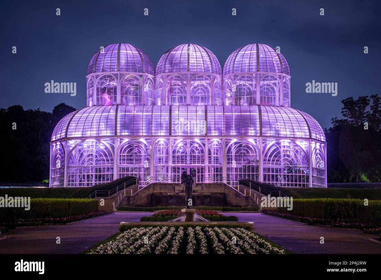 Beautiful view to glass greenhouse building shining purple at night Stock Photo