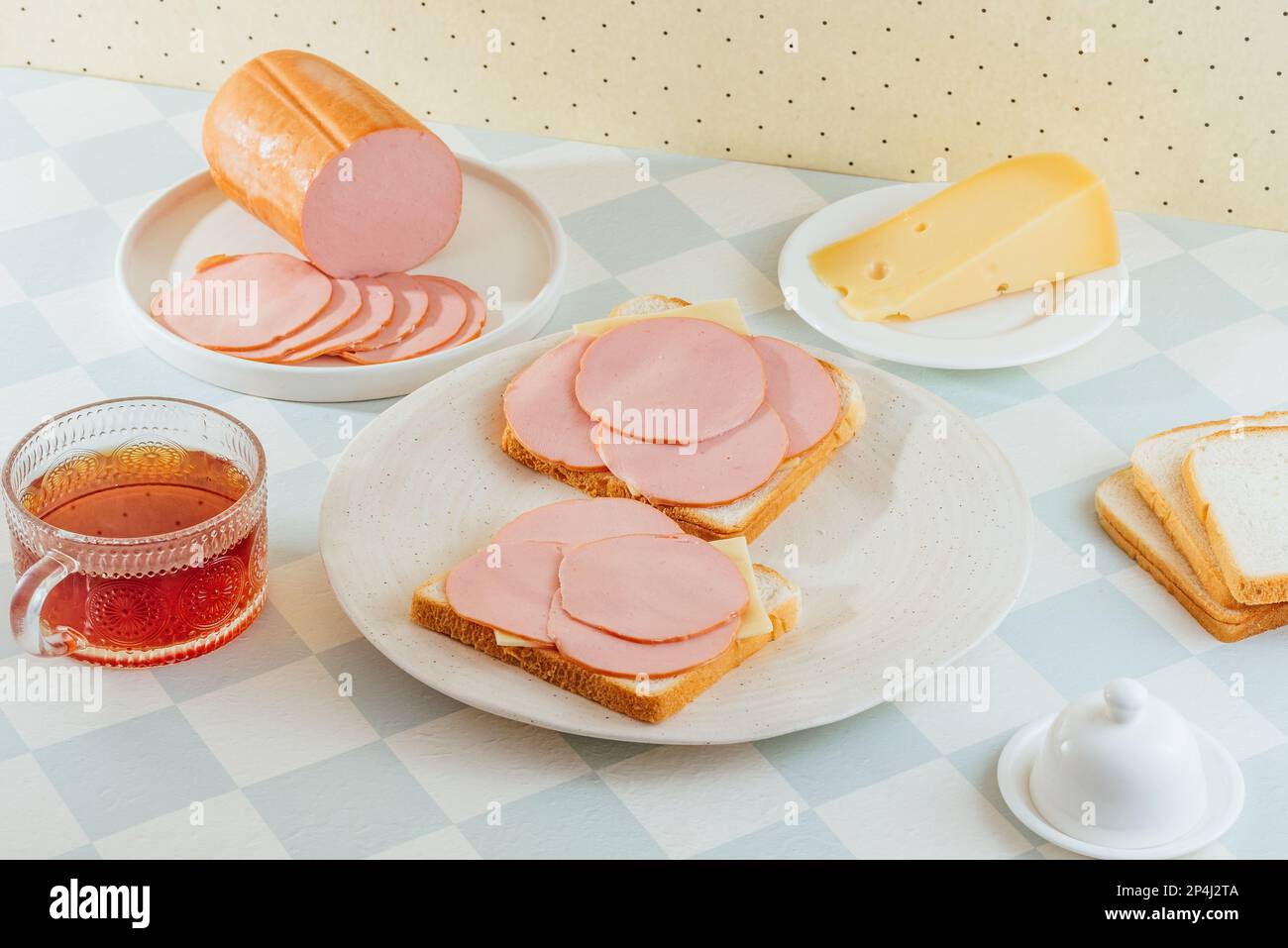 ham and cheese sandwich on a plate. ham is nearby. breakfast. Stock Photo