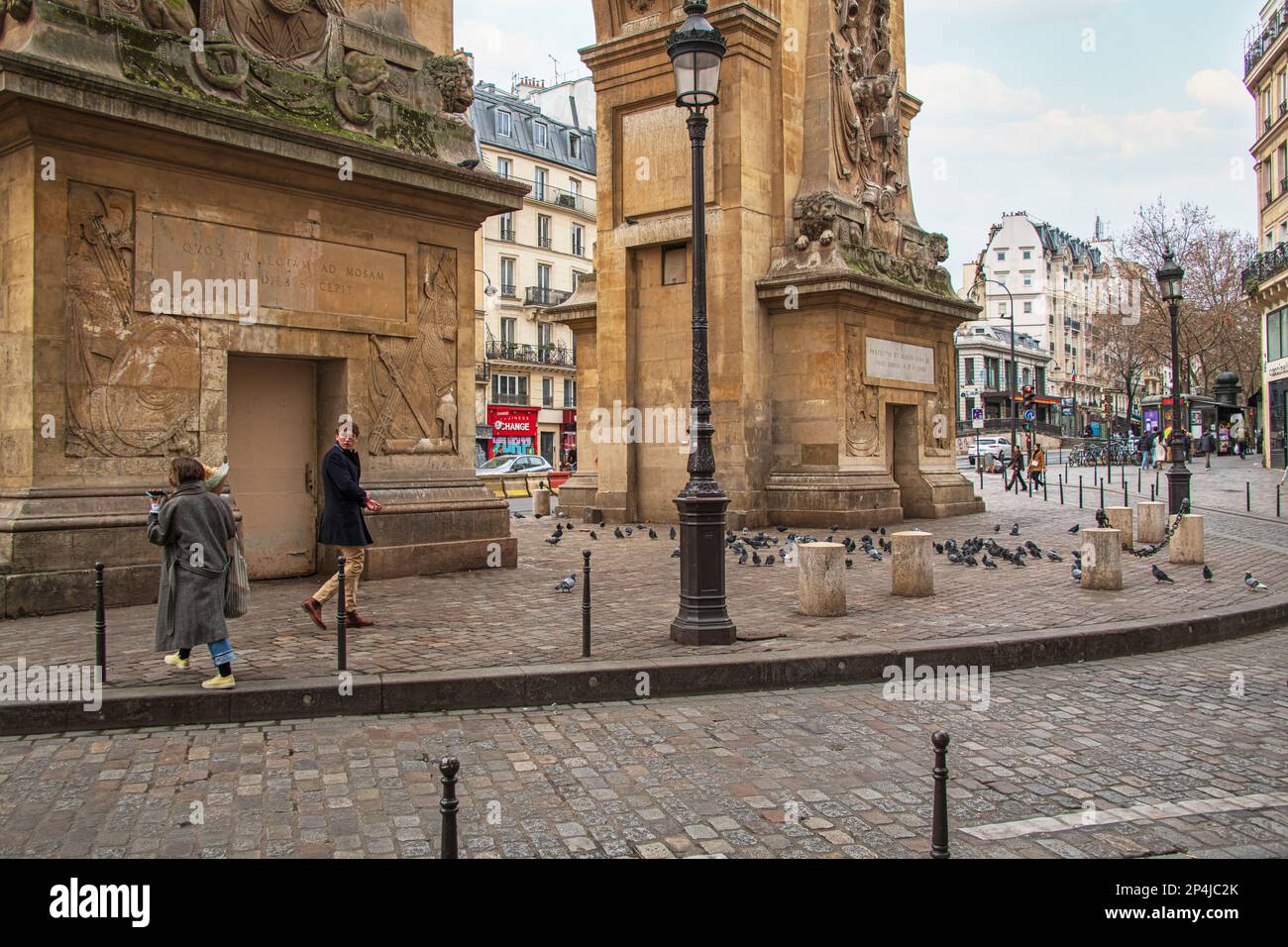 A Man turns to look at a passing women underneath the Porte Saint-Denis in Paris. Stock Photo
