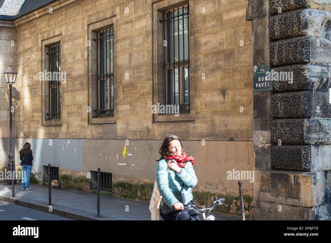 A women cycles along a street in the Marais area of Paris. Stock Photo