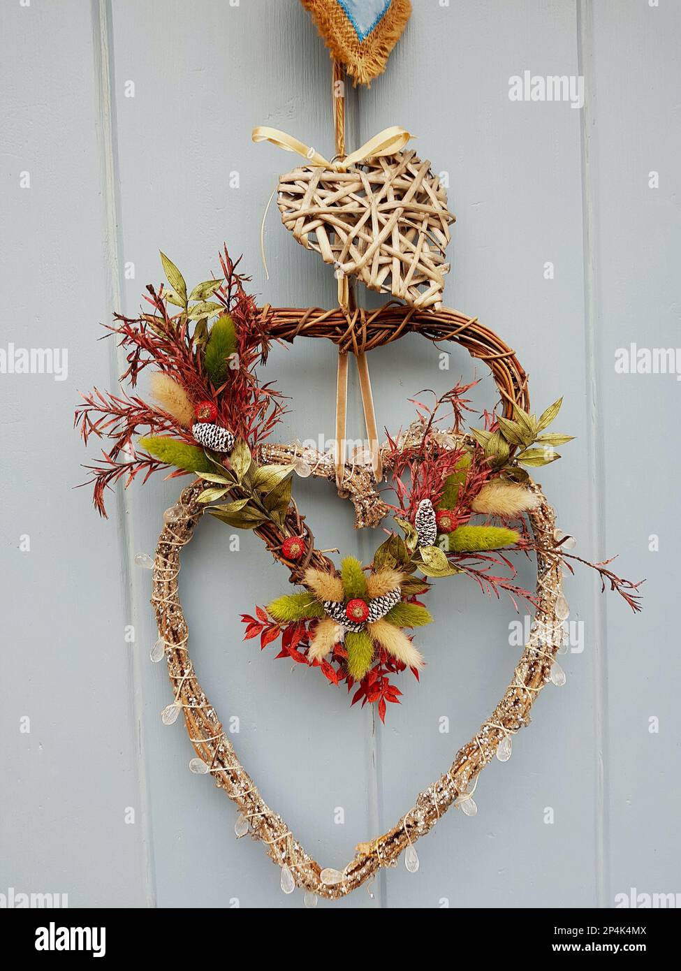 A seasonal heart shaped wreath on a grey wood panelled door. Stock Photo