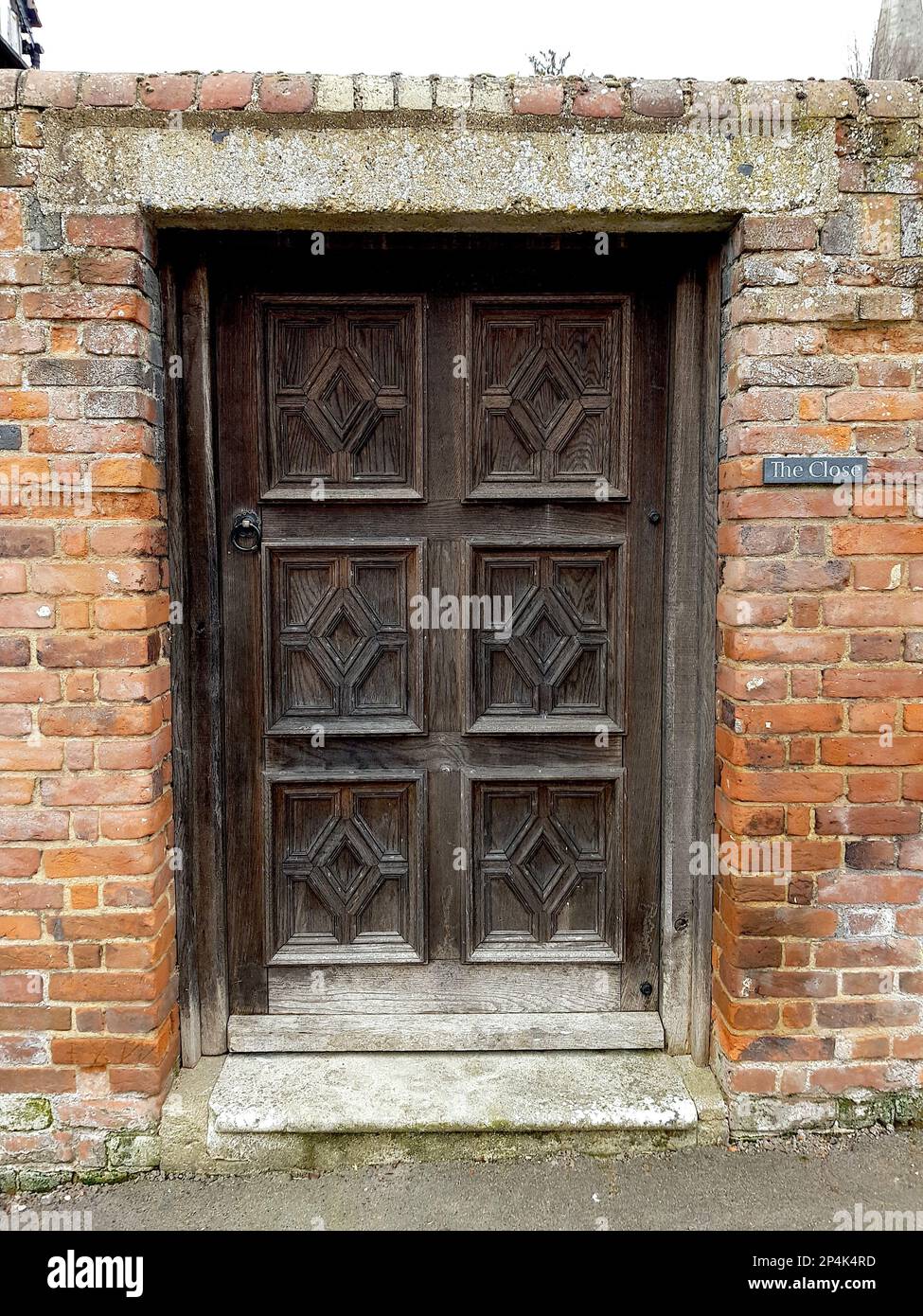 A traditional decorative wood panelled door set into a red brick wall. Stock Photo