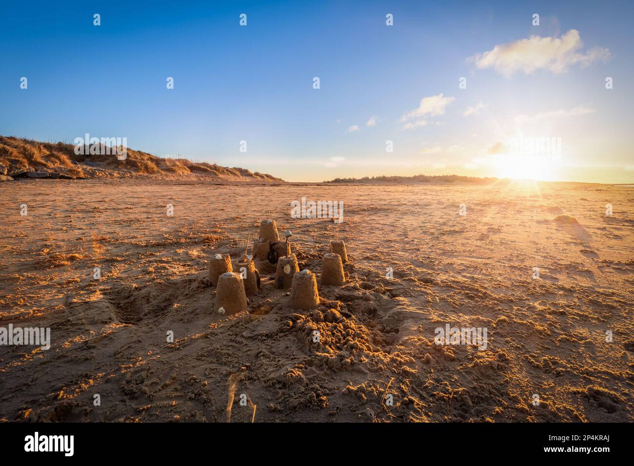 Sand castle on beautiful Brancaster  beach in Norfolk at dusk sunset with blue skies and light clouds Stock Photo