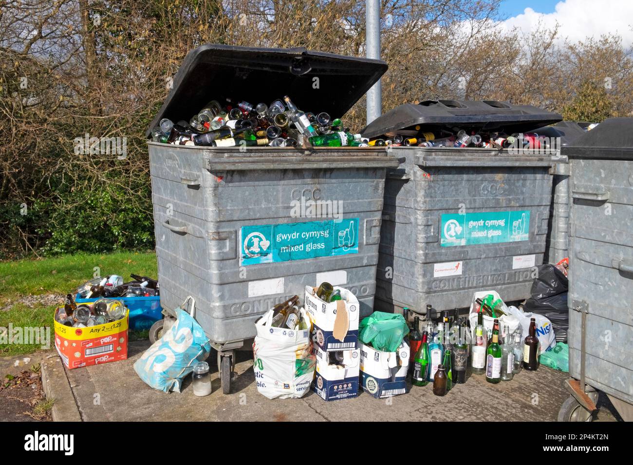 Glass bottles in bins containers and on ground at bottle recycling