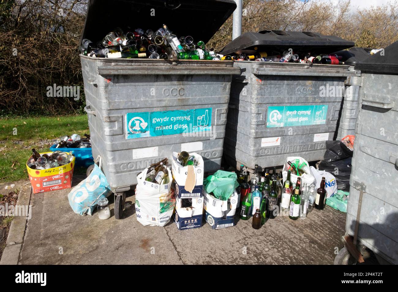 Glass bottles in bins containers and on ground at bottle recycling station in Carmarthenshire