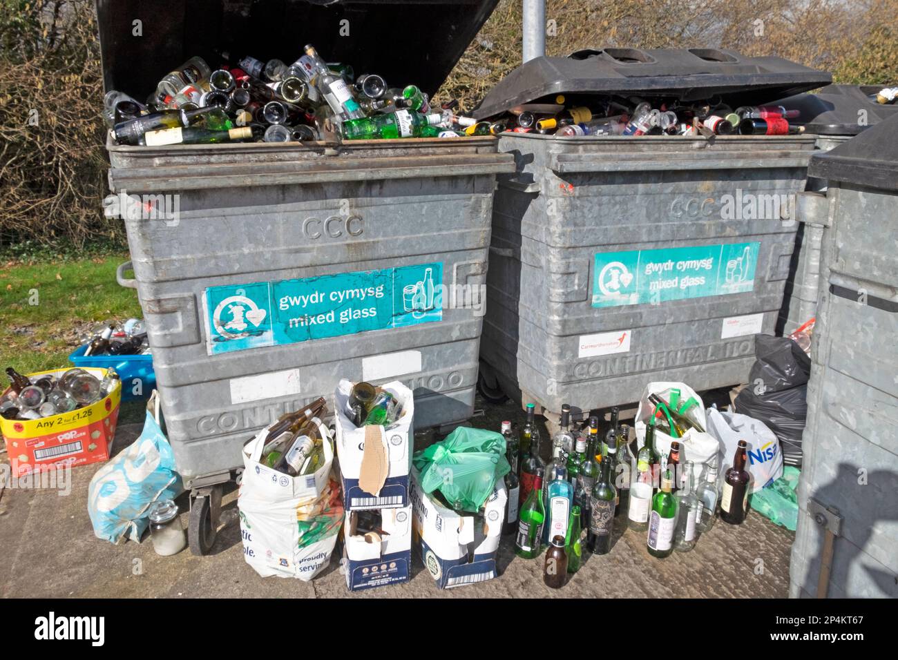 Glass bottles in bins containers and on ground at bottle recycling