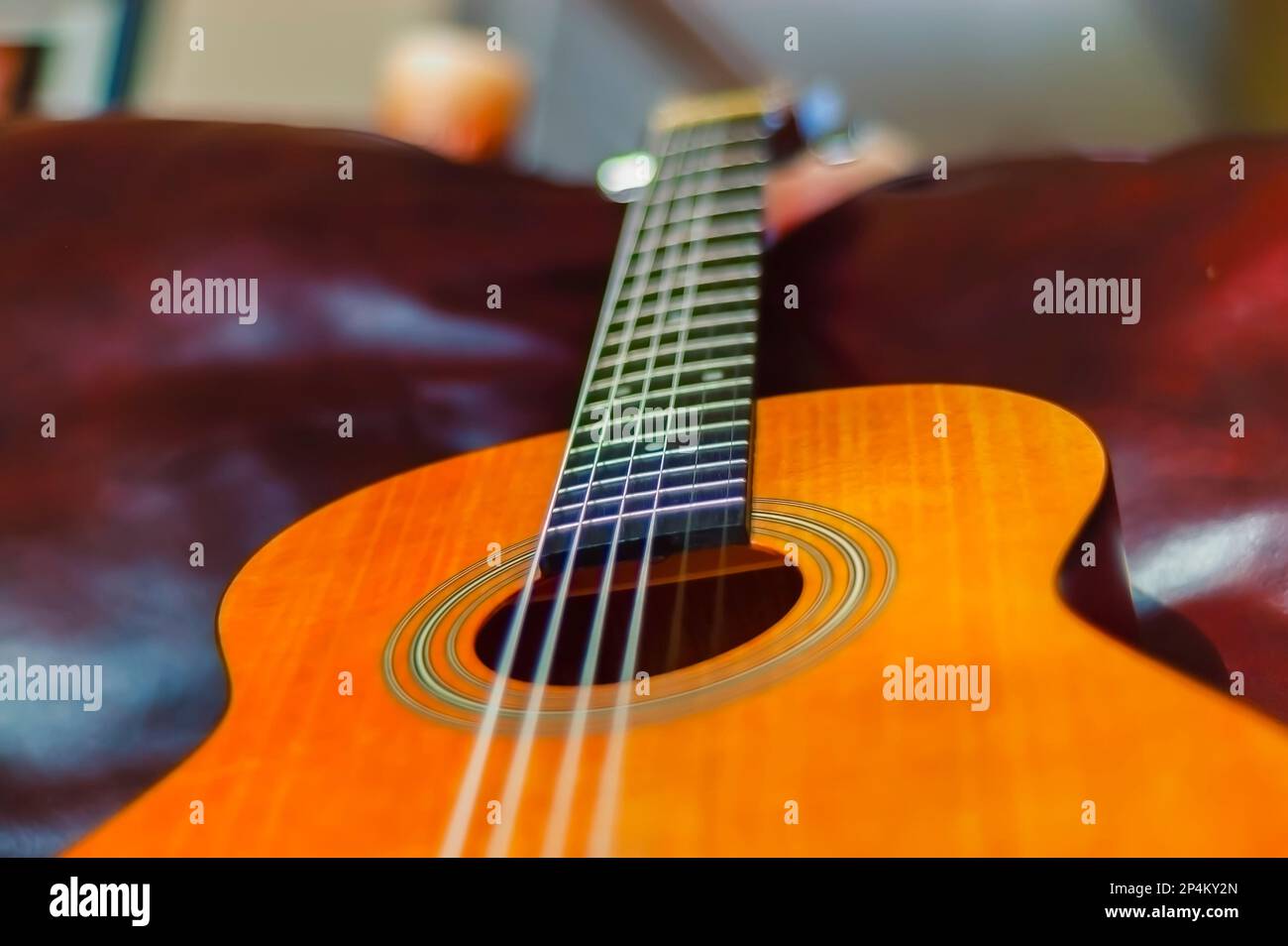 A close up of classical acoustic guitar with nylon strings, lying on a couch. Stock Photo