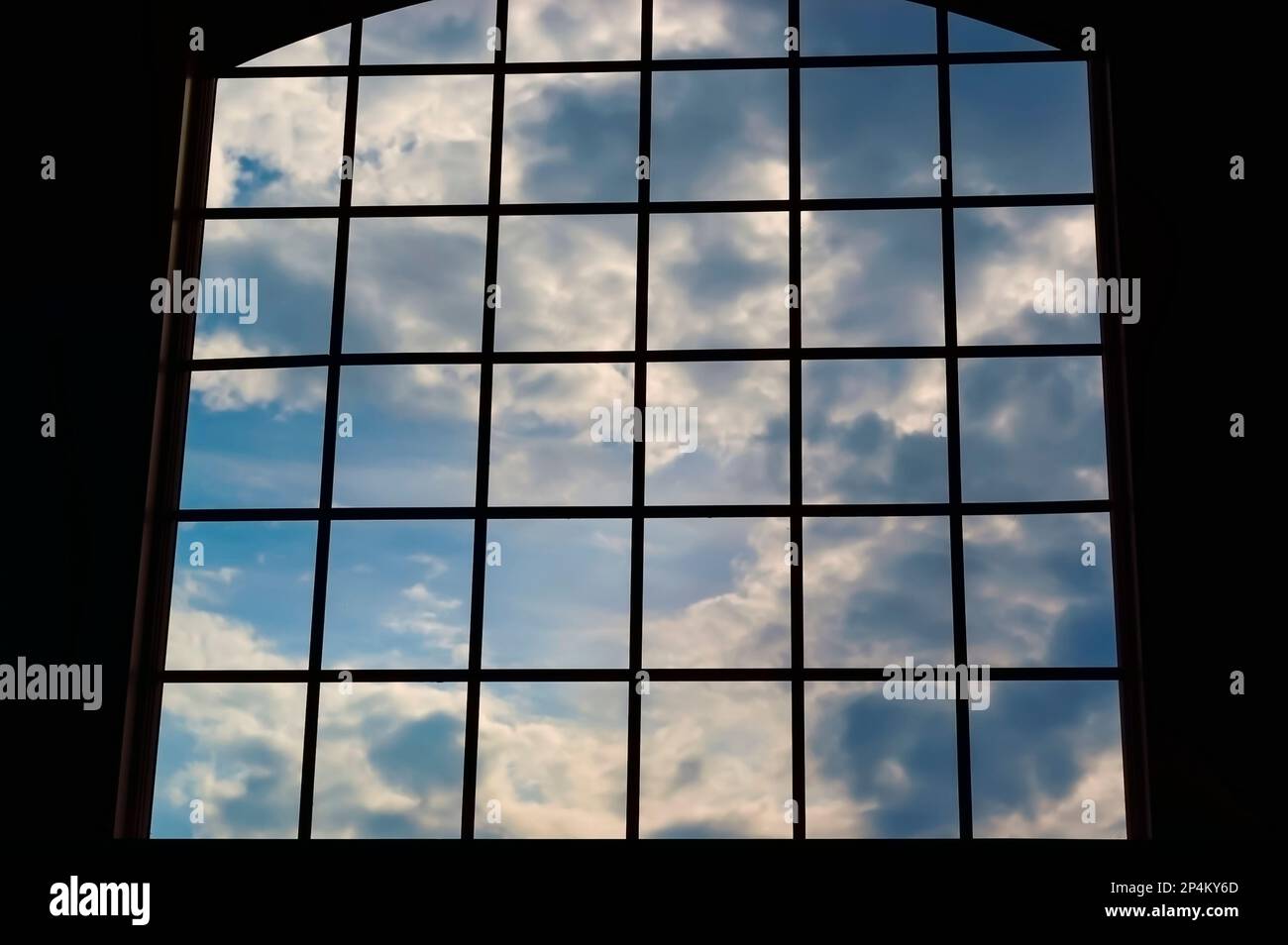A view of the sky with clouds through a large window with numerous square panes. Stock Photo