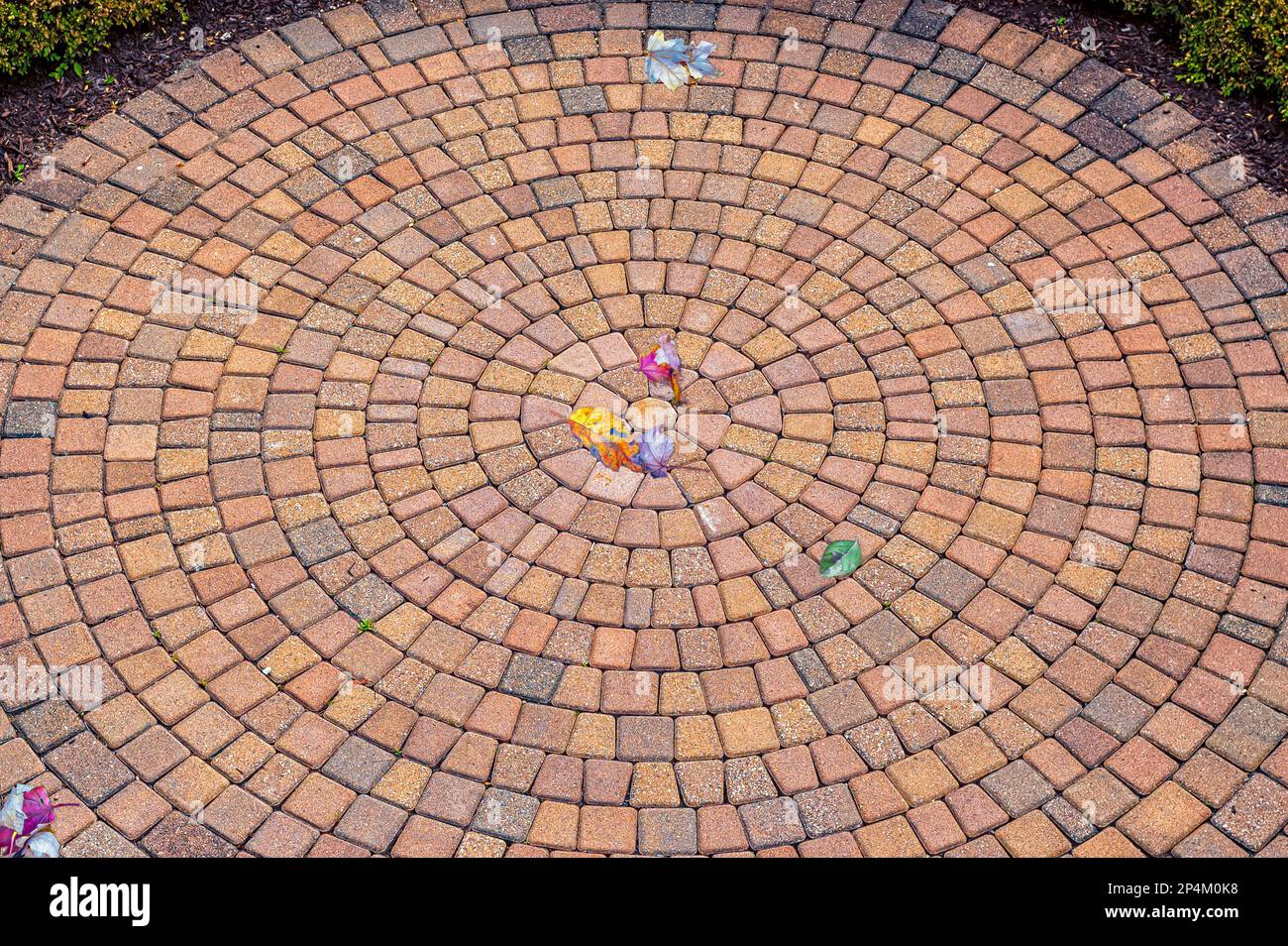 Bricks laid out in concentric circles in a yard. The layout creates an optical illusion of movement from the center/centre of the circle.. Stock Photo