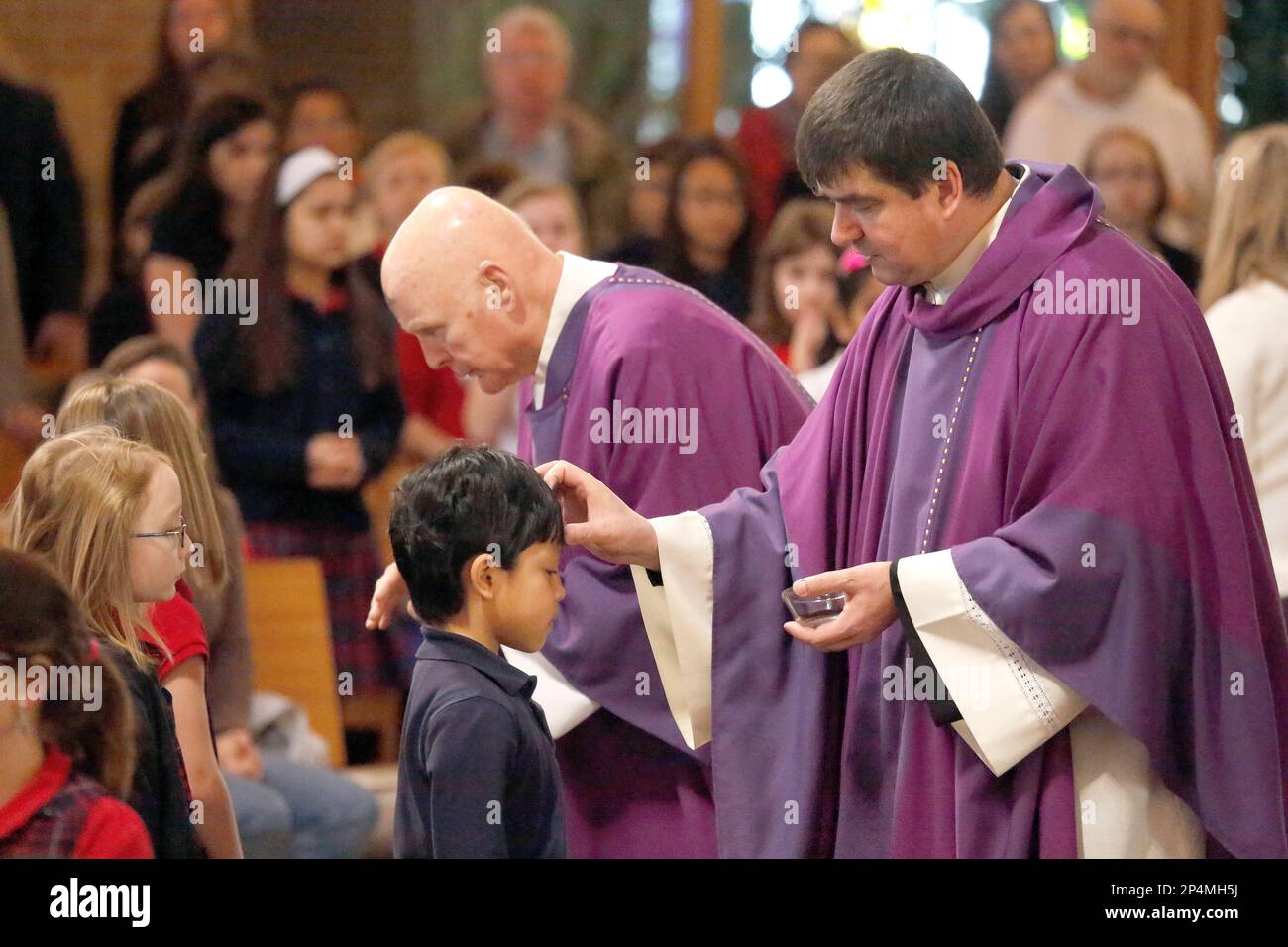 Father Peter Sarnicki, right, puts ashes on second grade St. Margaret