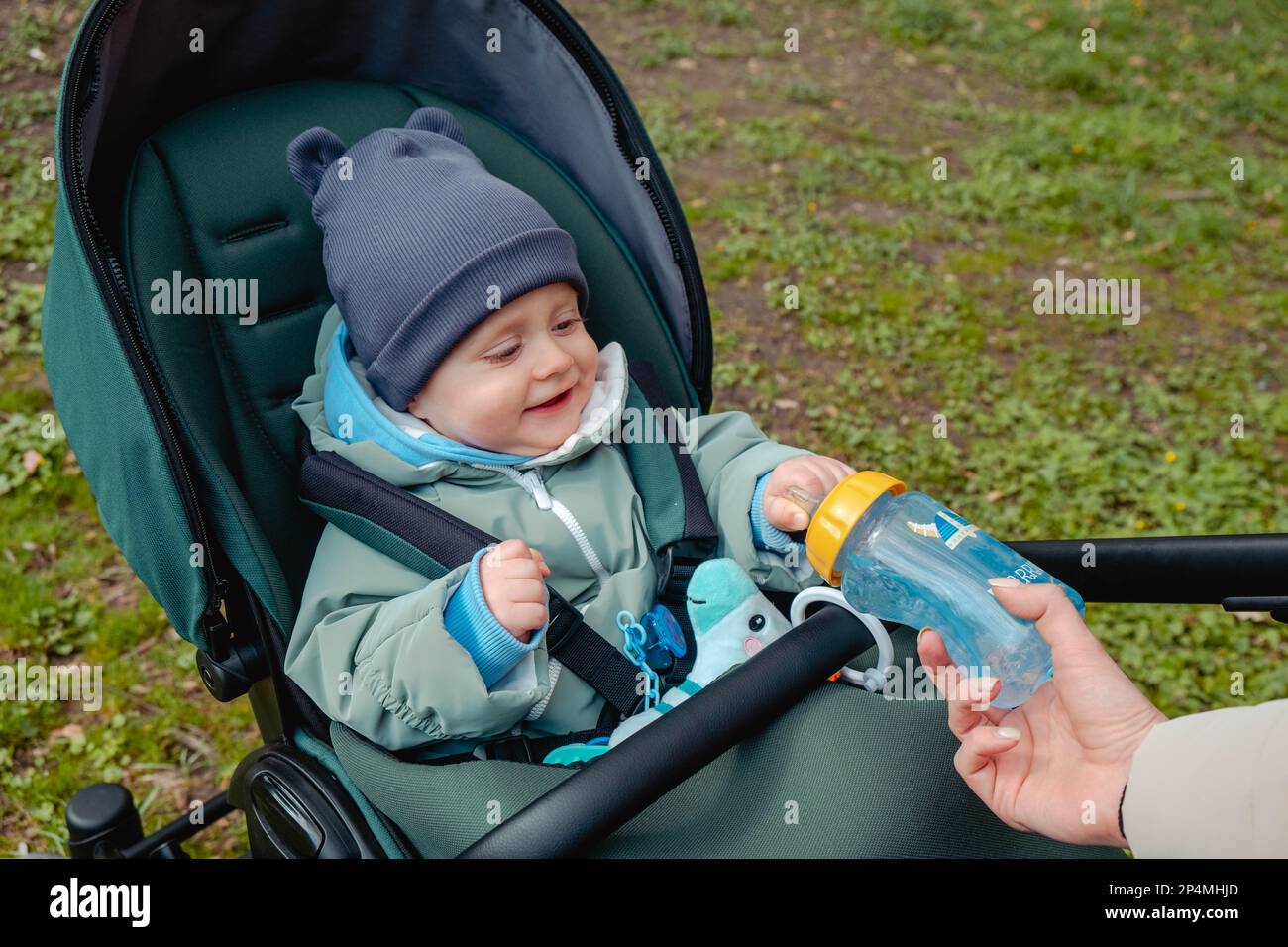 Surprised child in stroller holding bottle in spring park Stock Photo ...