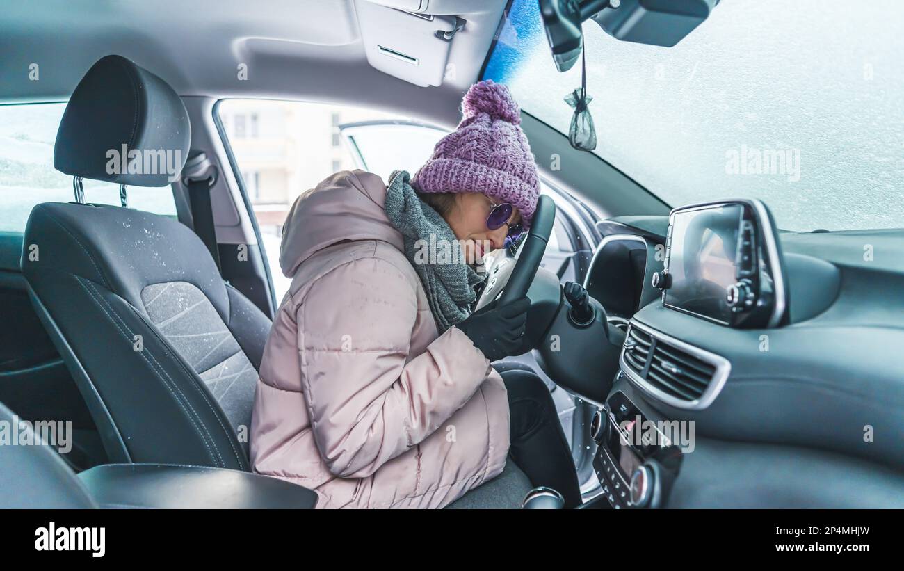 disappointed young woman in winter clothes sitting in the frozen car which does not work, winter concept. High quality photo Stock Photo