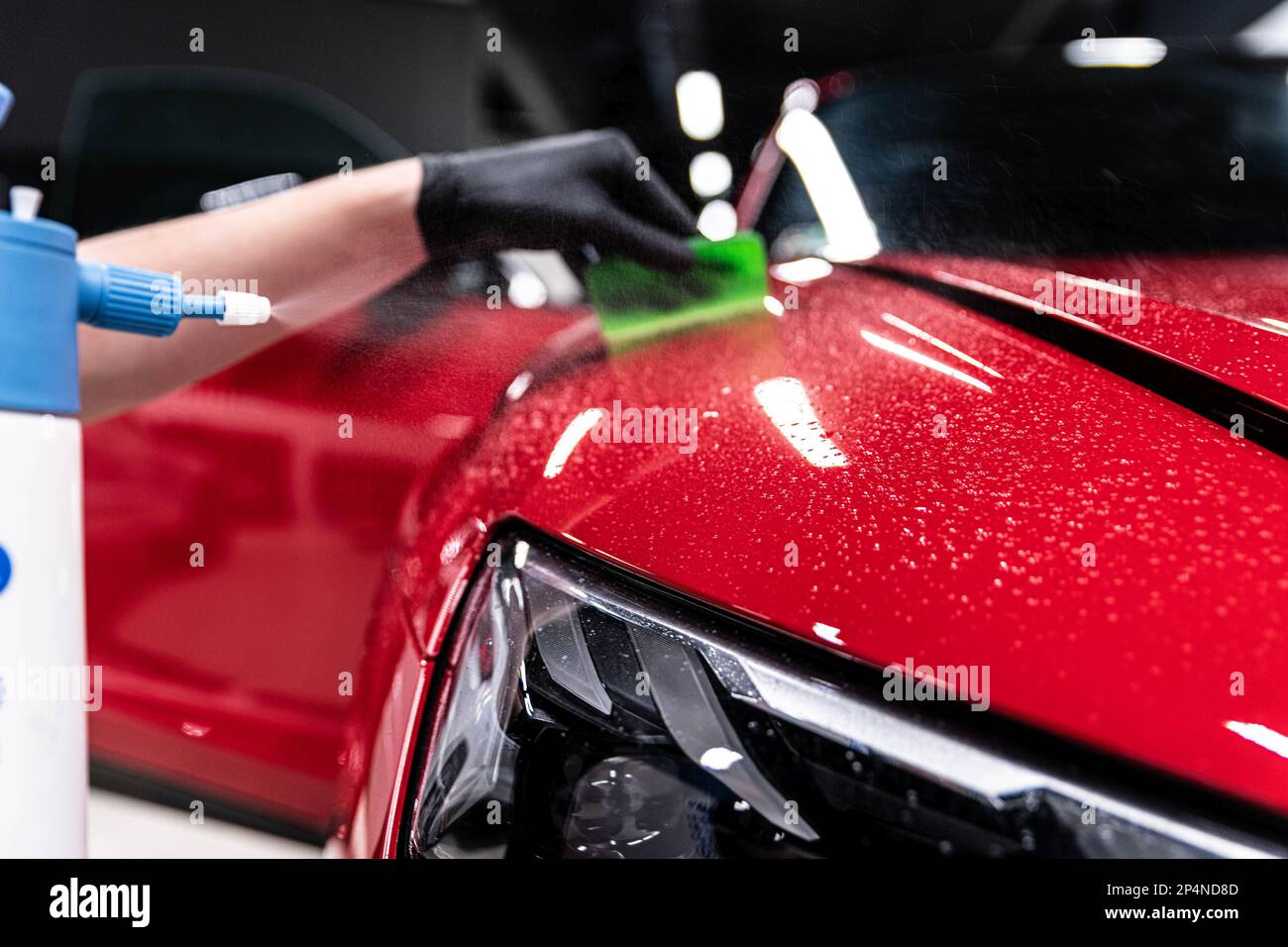 Application of a colorless protective film at a car detailing studio or car wash.  Stock Photo