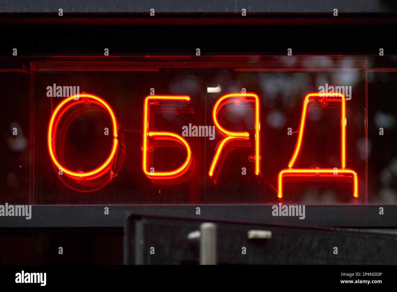 Red neon sign above the open door of a restaurant saying in Bulgarian
